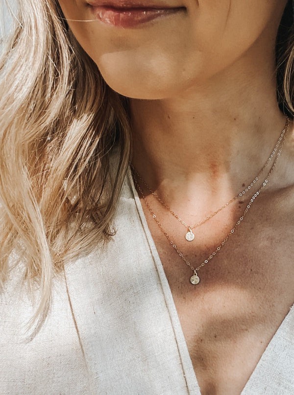 A gold-filled, minimalist oval necklace stamped with a cross.